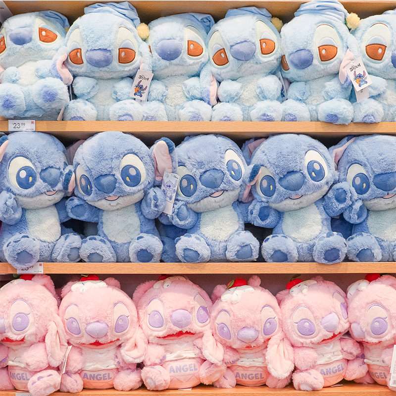 Shelves filled with blue and pink Stitch and Angel plush toys inspired by Disney’s Lilo & Stitch characters.