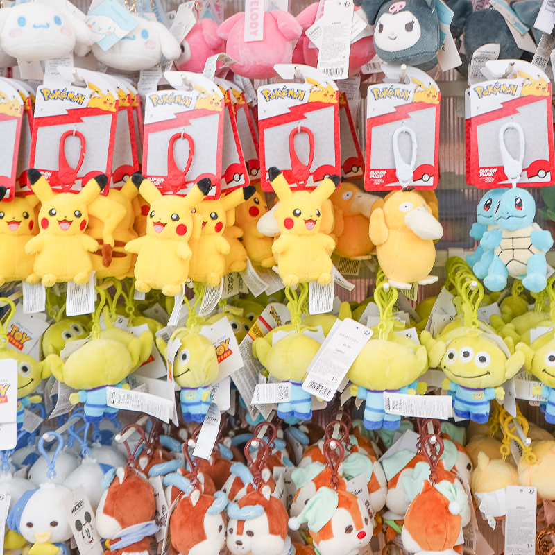 Retail display wall filled with plush character keychains including Pokémon, Disney, and Sanrio-inspired characters.